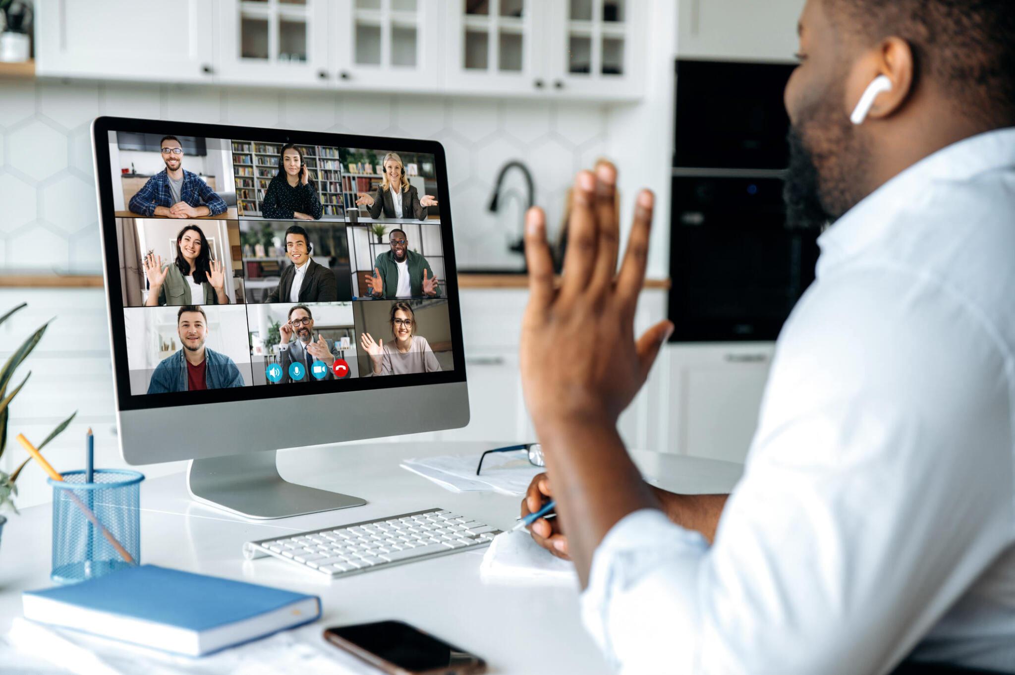A remote worker collaborating with other participants on video conferencing on his computer and using an apple airpods