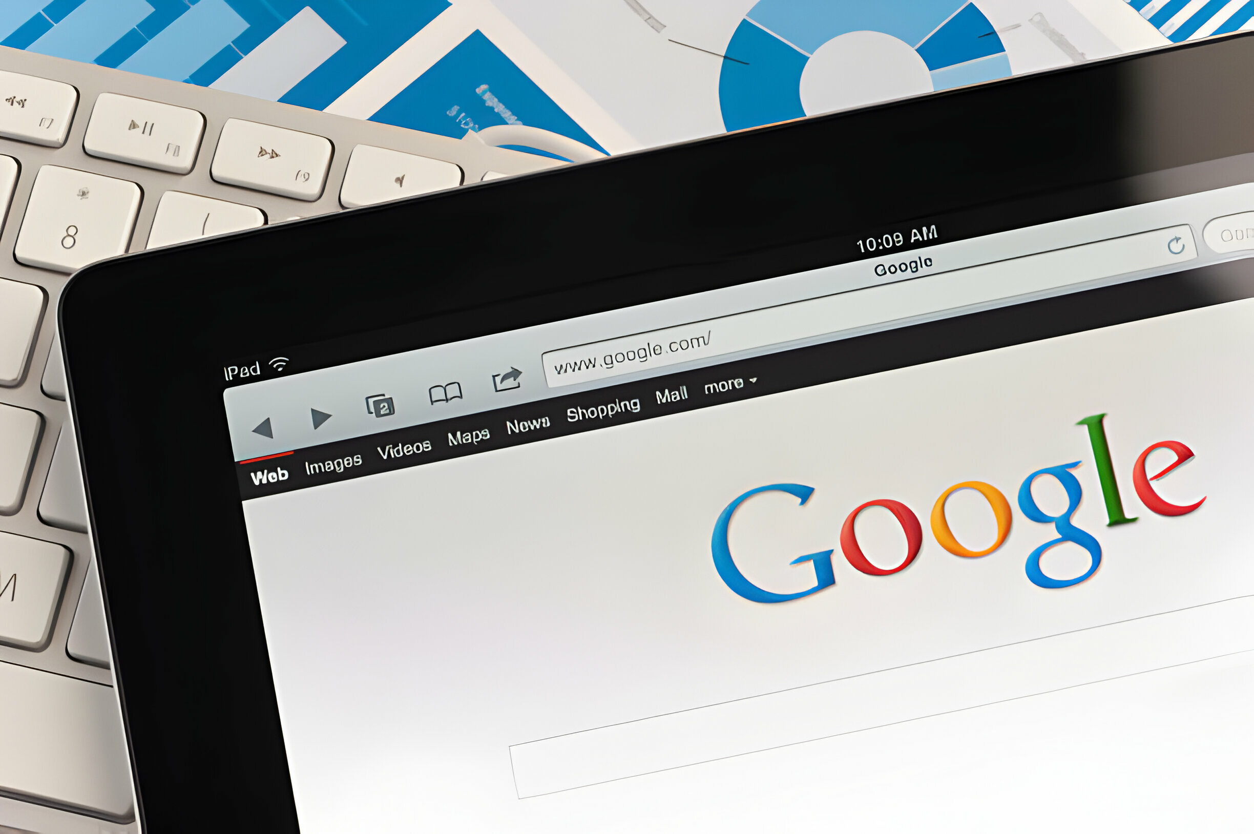 Close up of an Apple Ipad and on a desk showing the Google search engine home screen